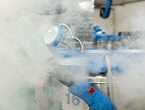 Un technicien ouvre une cuve remplie d'azote liquide, laissant échapper de la vapeur froide - Agrandir l'image (fenêtre modale)